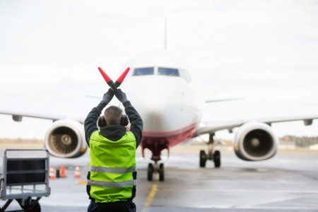 Sikkerhedsmedarbejder signalerer til fly på landingsbanen