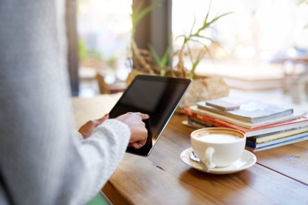 Kvinde arbejder på tablet på en café