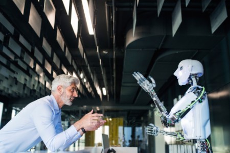 Videnskabsmand står overfor robot ved et bord