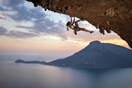 Ung kvinde klatrer på stor klippe