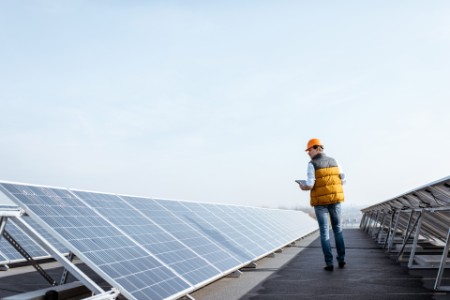 Mand tjekker solcelleanlæg på tag af bygning