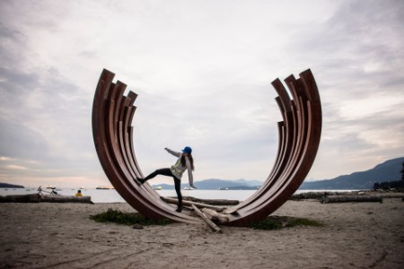 Kvinde står på buet skulptur på en strand