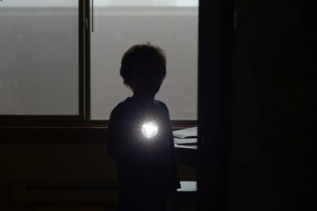 Ein Junge hält eine Taschenlampe in einem dunklen Raum