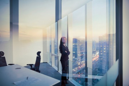 Geschäftsfrau in Büro mit Aussicht auf Stadt-Skyline