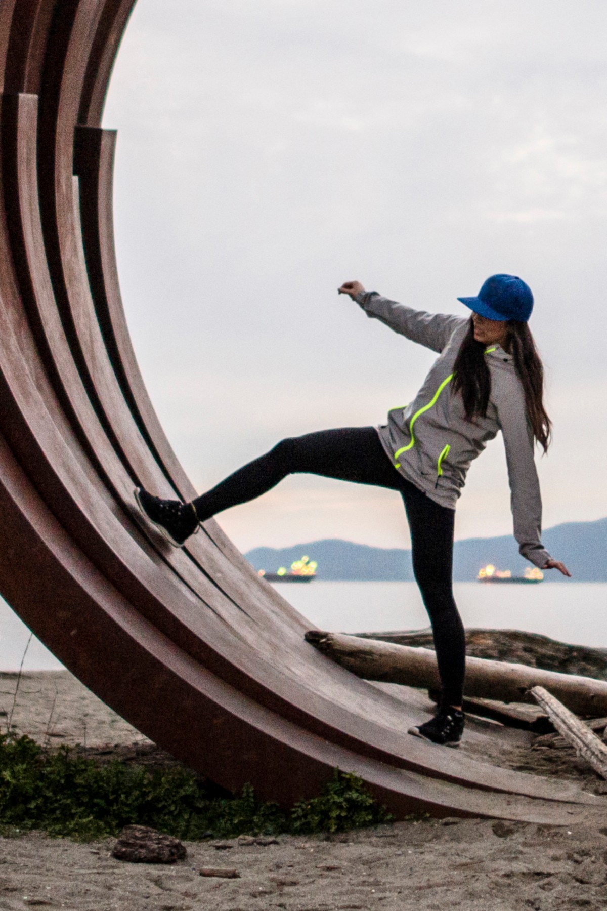 woman standing on arc sculpture, English bay, Vancouver, Canada