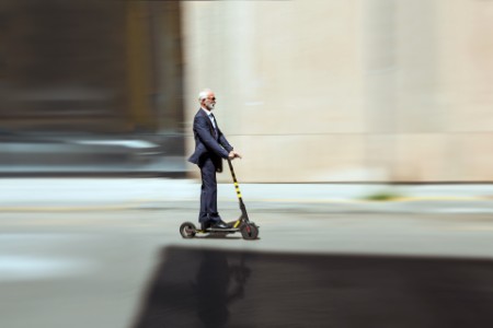 Geschäftsmann auf einem E-Scooter in der Stadt - Elektromobilität