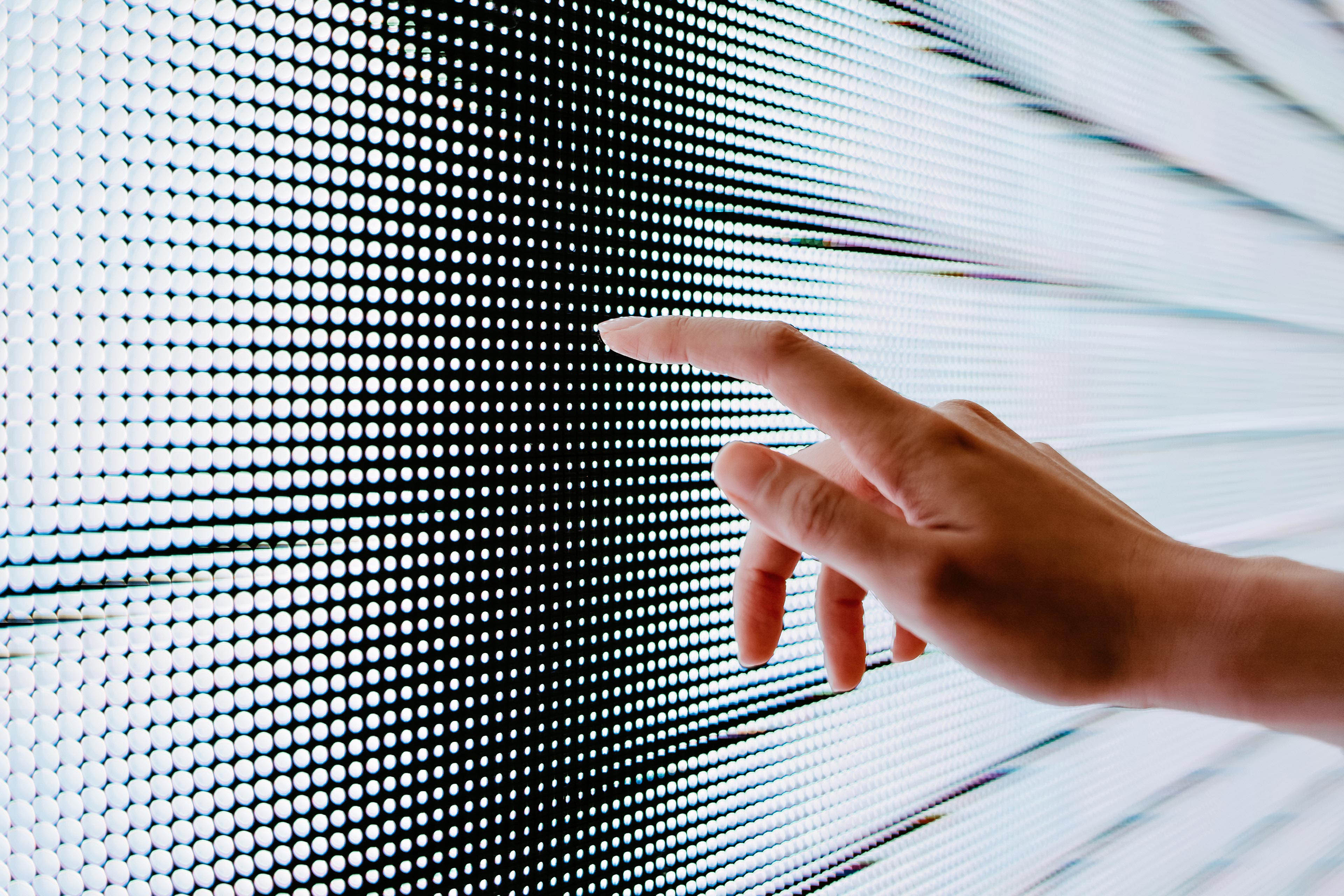 Nahaufnahme einer Frauenhand, die einen beleuchteten LED-Bildschirm berührt und sich mit der Zukunft verbindet