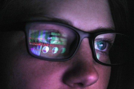 Frau mit Brille sitz vor einem Bildschirm