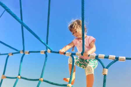 Kleines Mädchen klettert auf Strickleiter