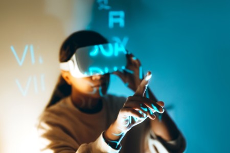 Moderne afroamerikanische Frau benutzt VR-Brille, um Zugang zu einer metaversen Welt zu erhalten