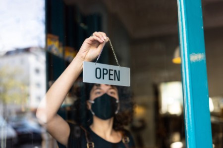 Frau hängt ein geöffnet Schild in einem Geschäft auf