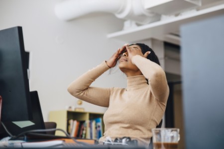 Frustrierte weibliche Computer-Programmierer mit Kopf in den Händen sitzen in kreativen Büro