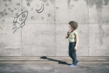 Neugieriges Kind schaut auf eine gezeichnete Rakete an der Wand