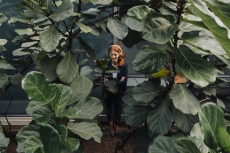 Geschäftsfrau hört Musik, umgeben von großen Pflanzen