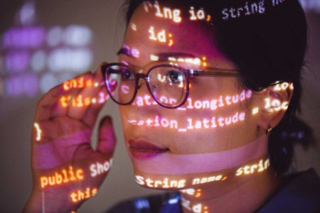 Porträt einer Programmiererin mit auf ihr Gesicht projiziertem Programmcode
