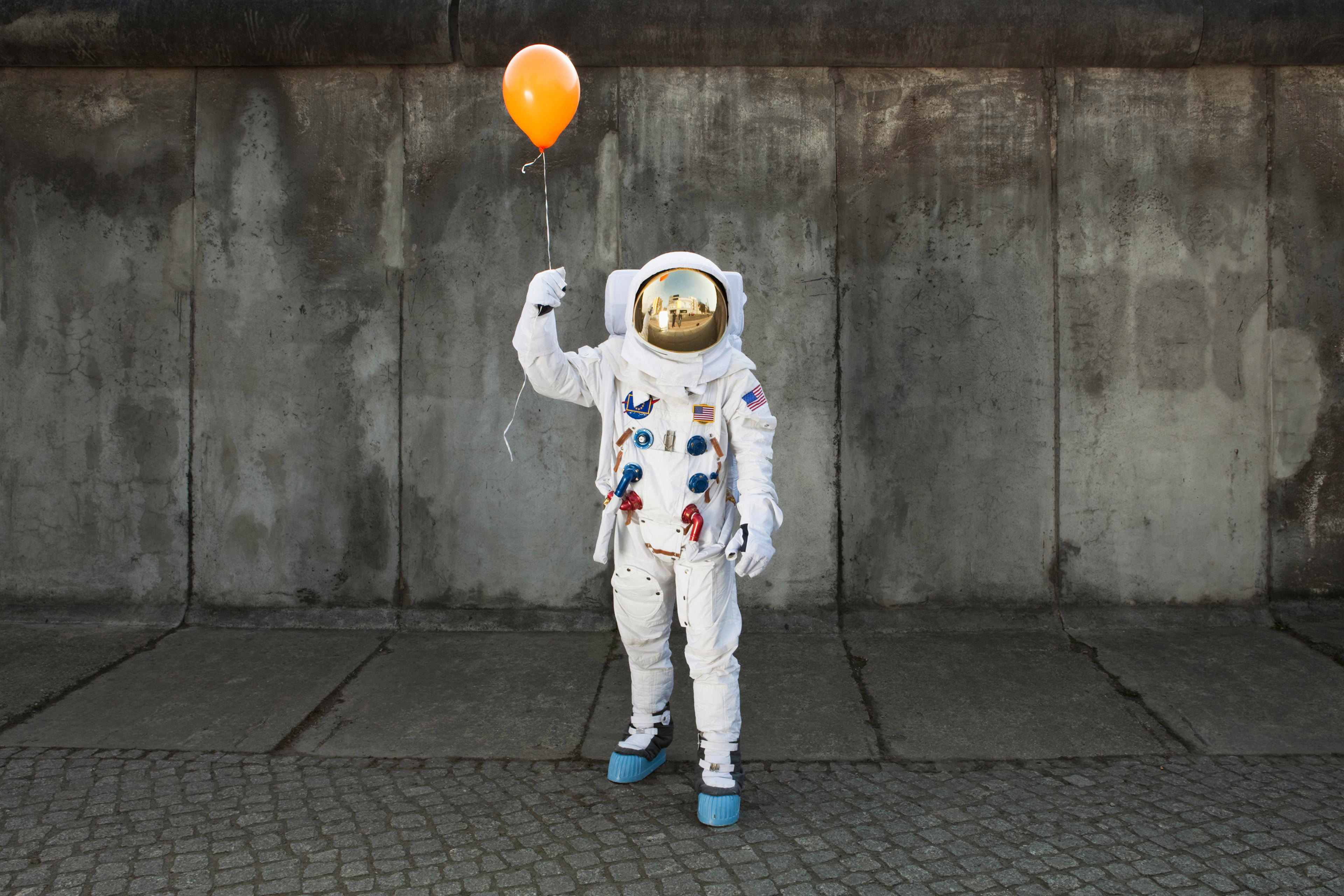 Ein Astronaut mit einem Luftballon auf dem Bürgersteig einer Stadt