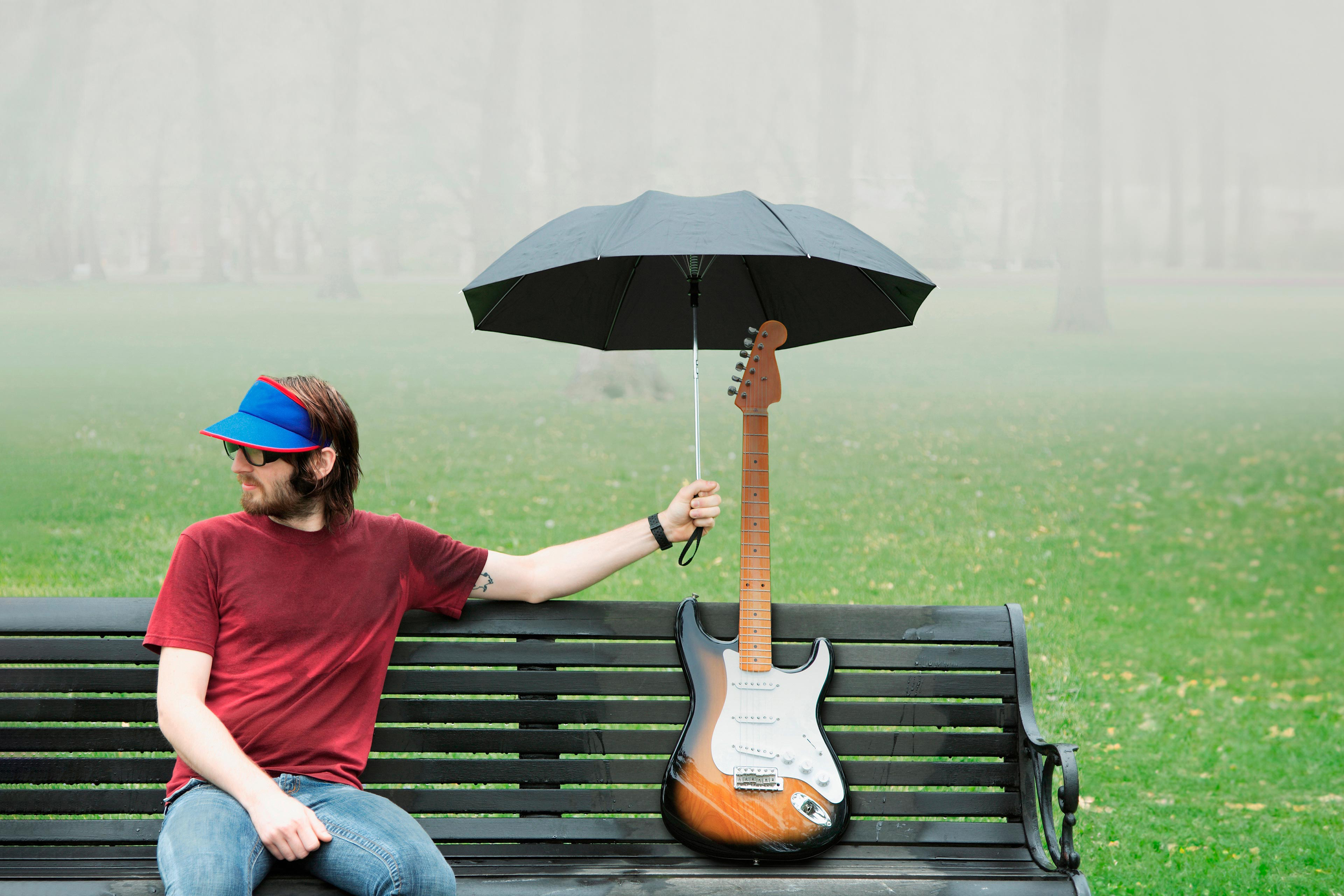 Mann hält Regenschirm über E-Gitarre