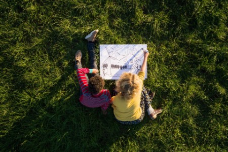 Junge und Mädchen zeichnen im Gras