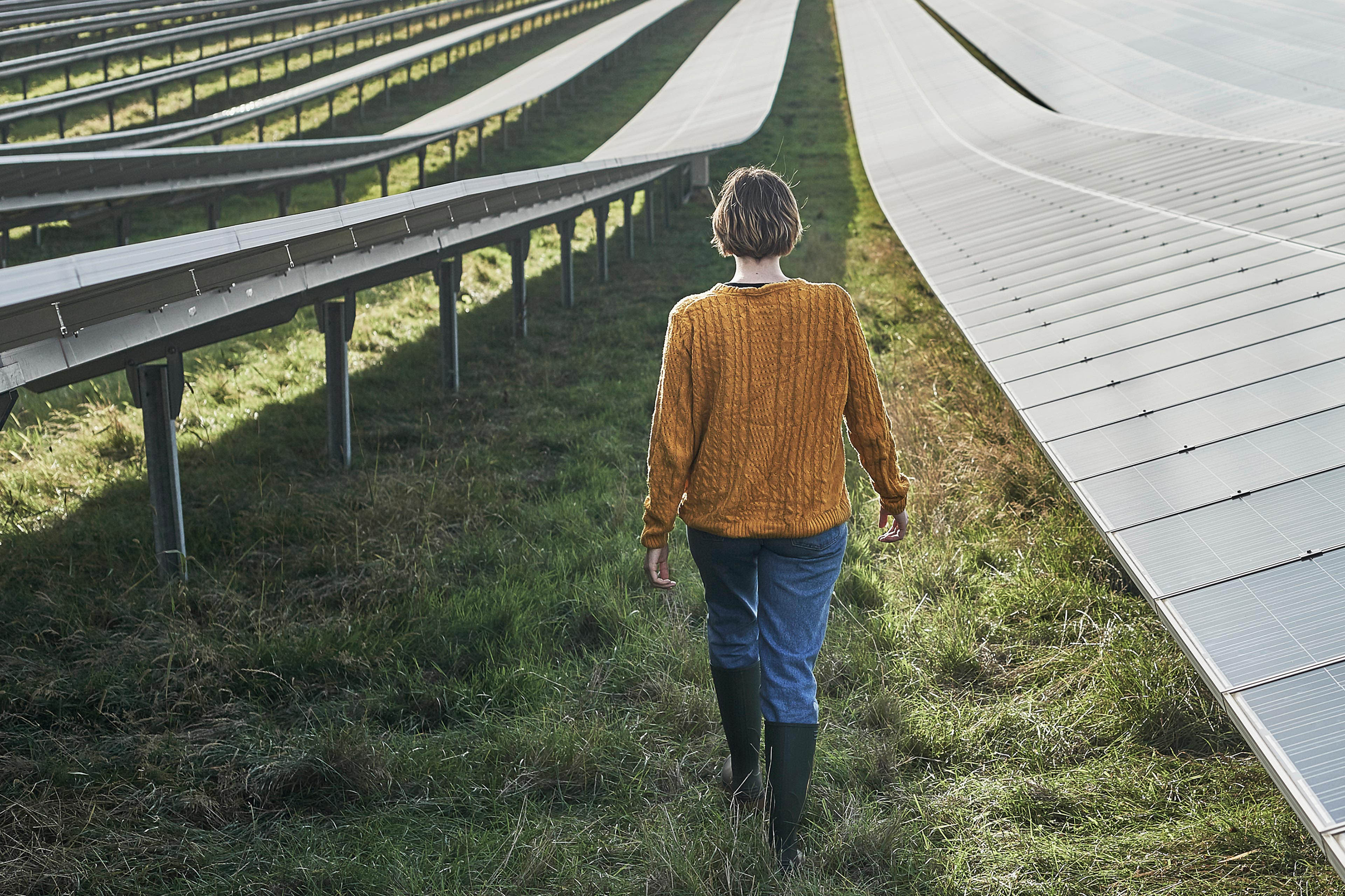 Junge Bäuerin geht durch einen Solarpark