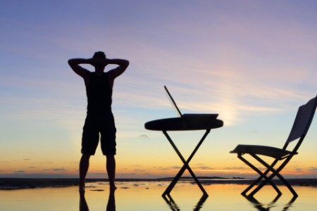 Mann steht neben Schreibtisch am Strand