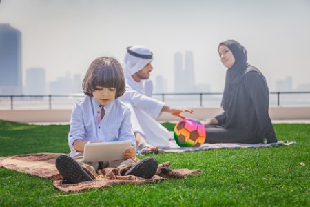 Middle eastern little kid playing game digital touchpad park father mother