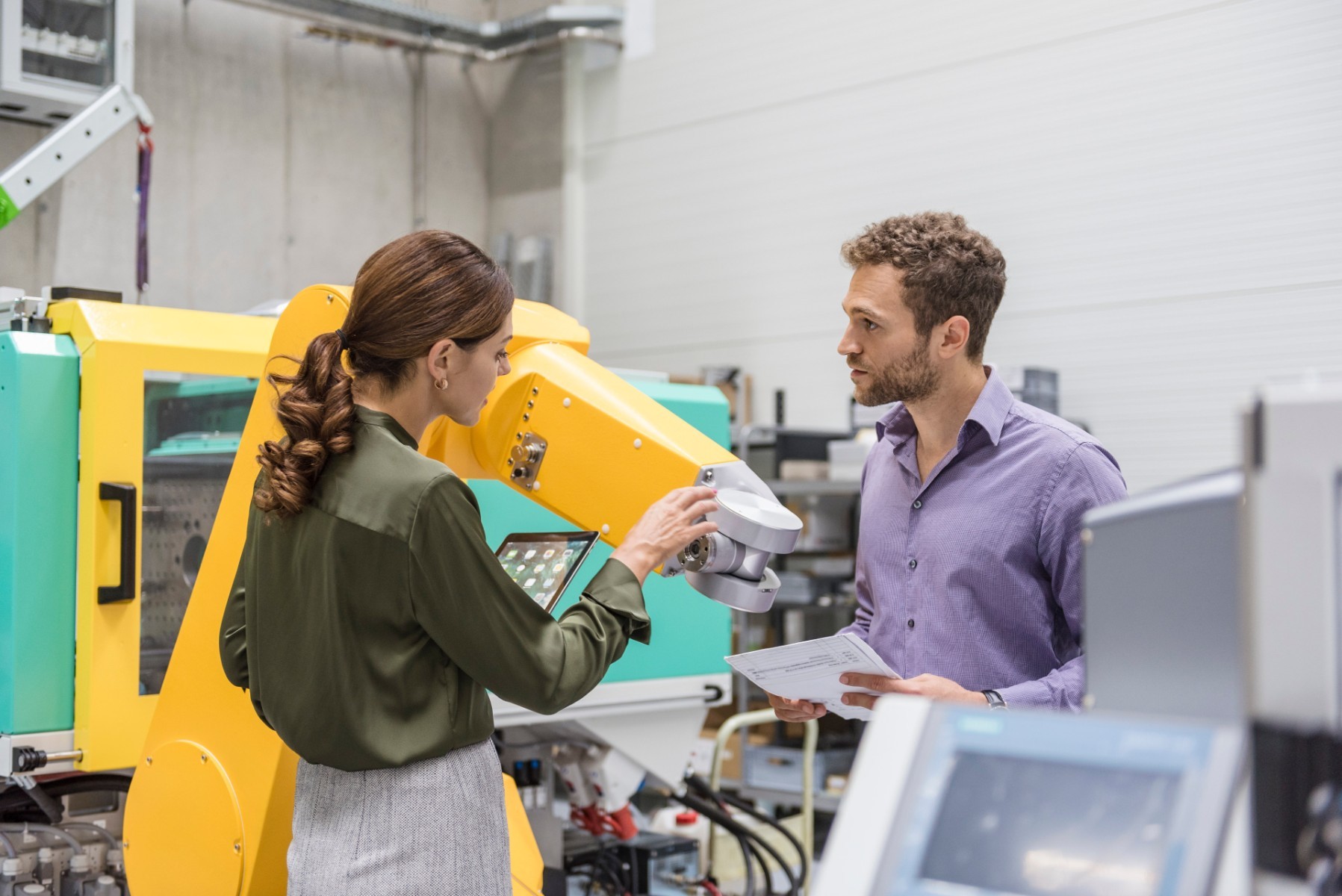 Two professionals meeting in front of industrial equipment