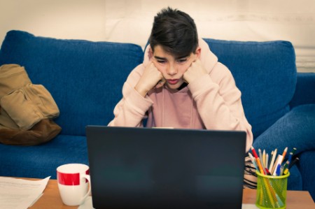 Teenage boy looks dispirited in front of computer