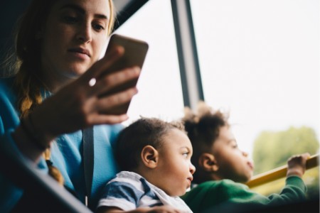 Mother using mobile & Kids sitting in window seat