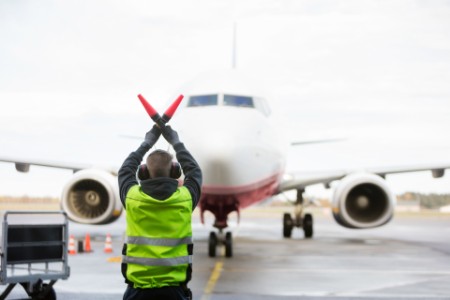 Ground worker signaling to airplane on runway