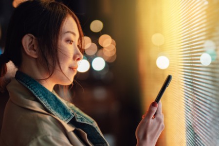 Young woman using crypto investment app on smart phone
