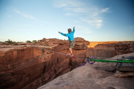 Guy walking on a line over a canyon in Moab