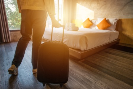 Cropped shot of tourist woman pulling her luggage to her hotel bedroom after check-in. Conceptual of travel and vacation. 