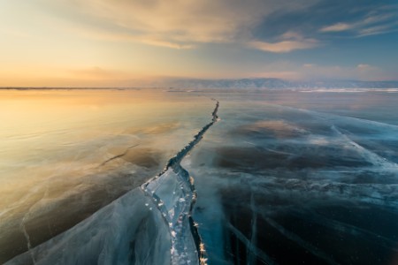 Sunset on the ice with cracks lake Baikal in winter