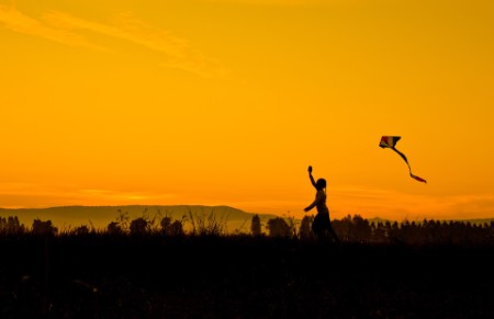 girl running with kite at sunset