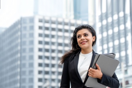 EY ‑ Femme portant des cartables devant des immeubles de bureaux