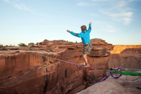 EY - Man walking tightrope over canyon