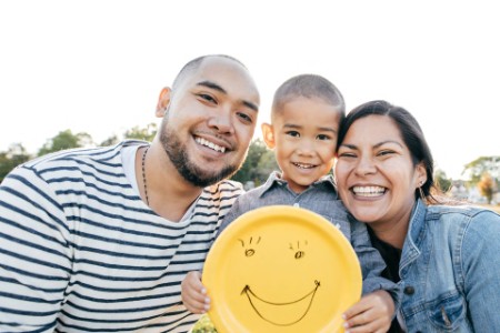 EY - Deux adultes et un enfant tenant une plaque de visage heureux