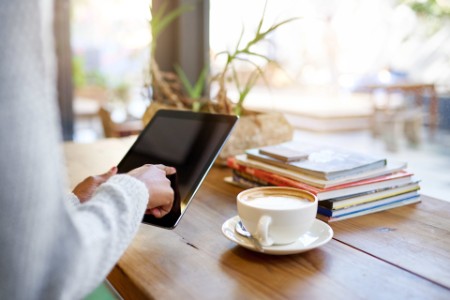 EY - Woman sitting in a cafe using her tablet