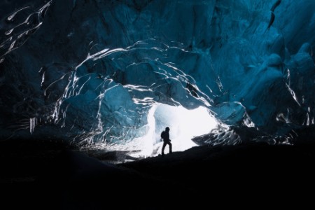 EY - Man exploring an amazing glacial cave in Iceland