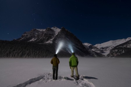 EY - Couple stand in snowy clearing with headlamps