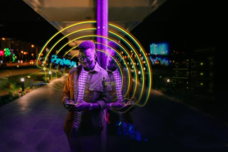 EY - Young man using Phone in a front of neon lights on the street