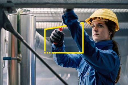 Female technician at work wearing yellow helmet