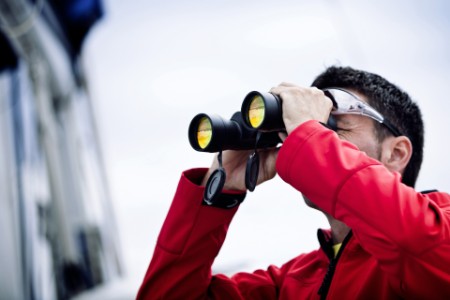Sailor with binoculars on sailboat