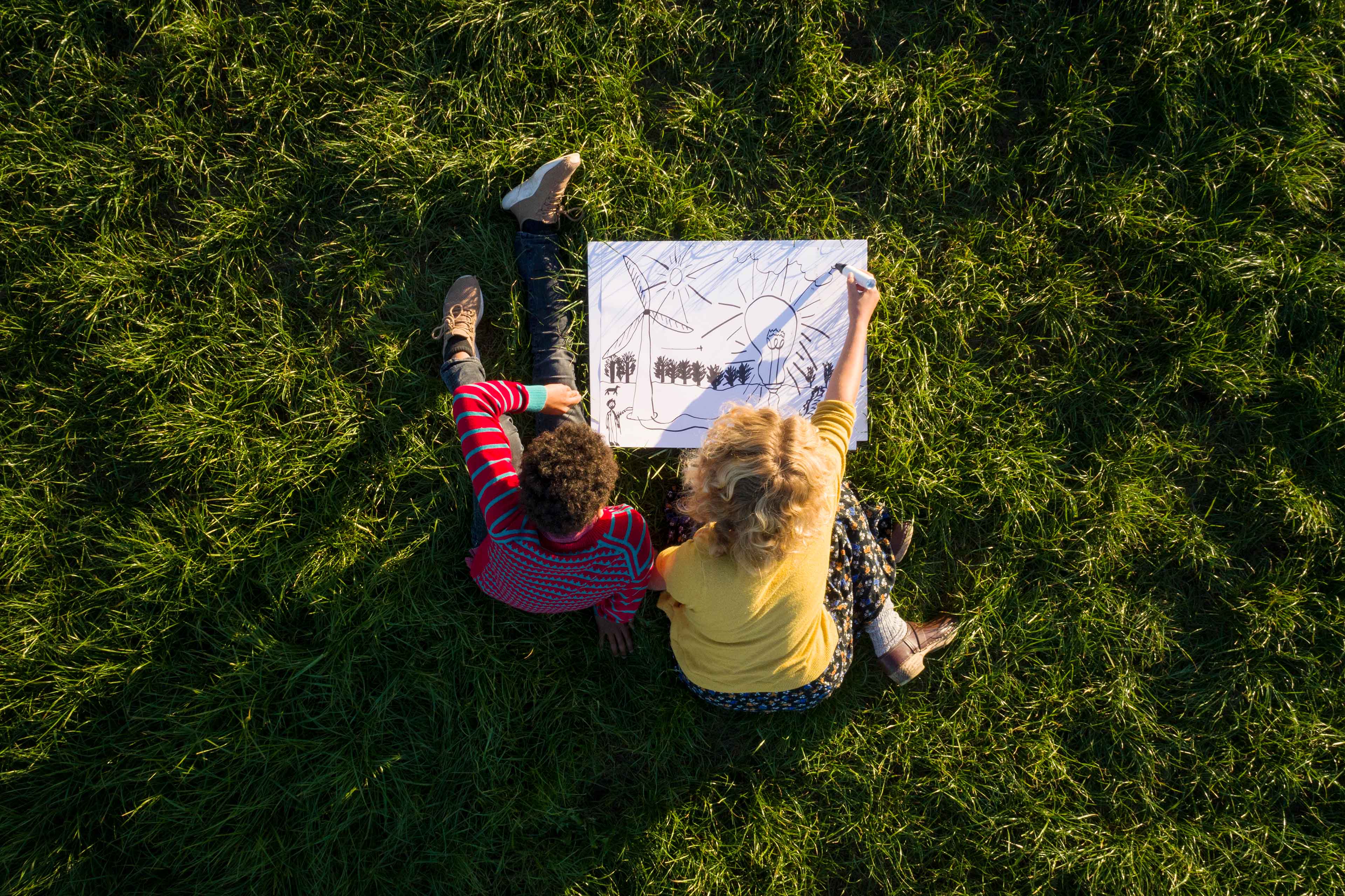 Boy and girl on grass drawing sustainable energy solution
