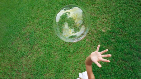A girl playing with soap bubble in green grass area