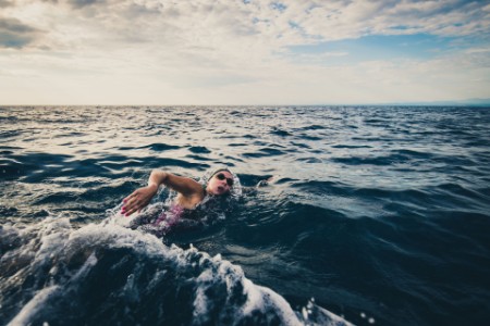 Female open water swimmer swimming forward crawl in sea