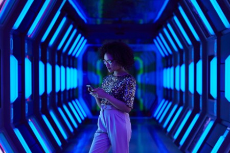 young women looking at smartphone in spaceship like corridor
