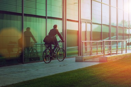 Man riding bicycle beside the modern office building
