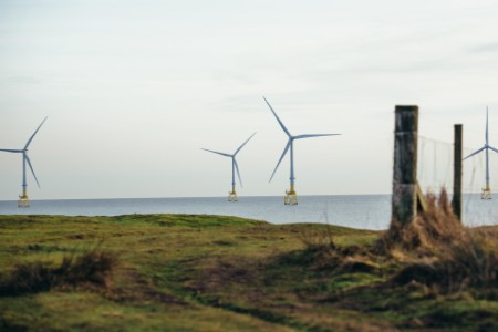 Offshore wind turbines in calm water seen over coastline