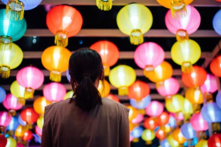 Asian woman looking up and admiring the hanging Chinese lanterns 
